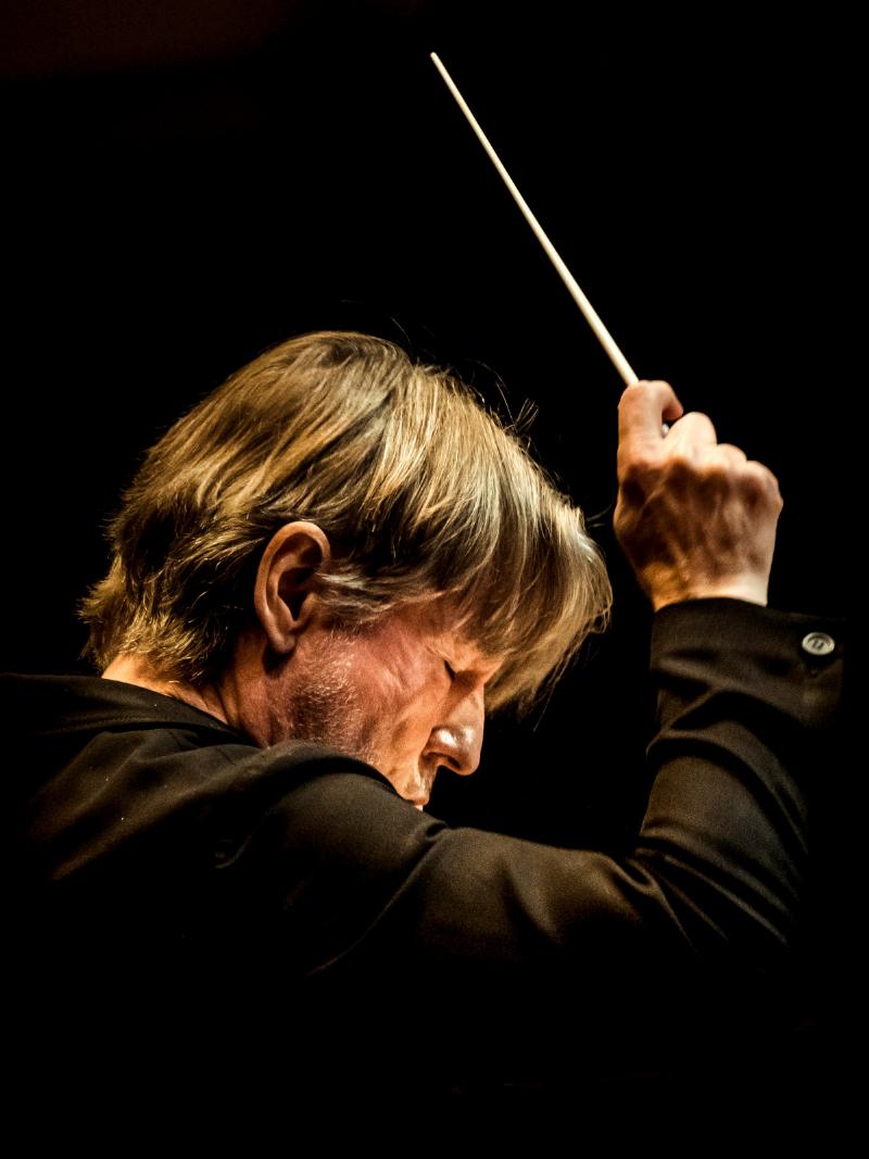 Un chef d’orchestre charismatique dirigeant un orchestre symphonique lors d’un concert à la Philharmonie de Paris